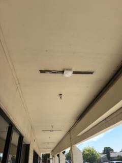 Covered outdoor walkway with ceiling-mounted lighting and structural beams