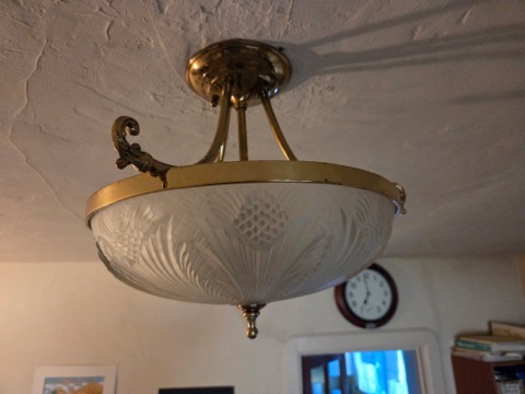 Brass semi-flush ceiling light fixture with frosted glass bowl shade in living room