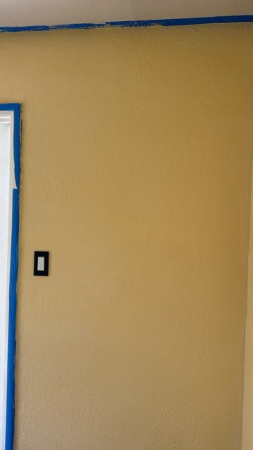 Yellow wall with blue painter's tape and electrical outlet