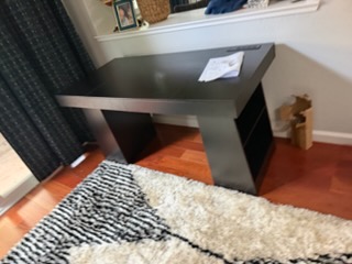 Modern gray desk with keyboard on wooden floor and patterned rugs
