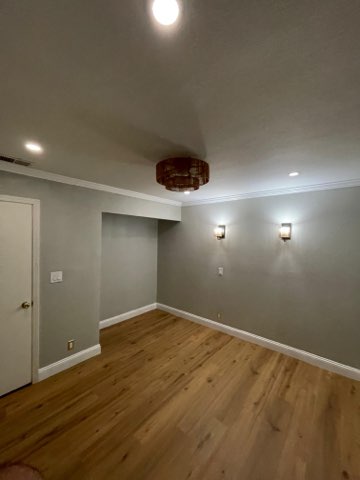 Empty room with wood flooring, gray walls, recessed lighting, and wall sconces
