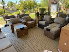 Outdoor furniture showroom with brown wicker seating, cushions, and wooden table on deck