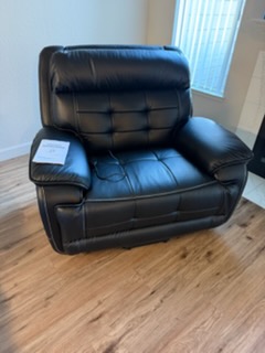 Black leather reclining armchair with quilted backrest on wooden floor