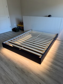 Modern black platform bed with white headboard and metal slat base in bedroom
