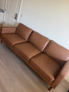 Brown leather sofa with cushions in a bright room with wooden flooring