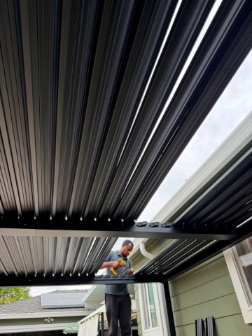Technician installing motorized retractable awning on residential patio