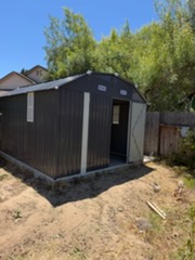 Dark metal shipping container converted into a backyard structure with door and window