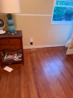 Modern living room with hardwood flooring, wooden dresser, and large window