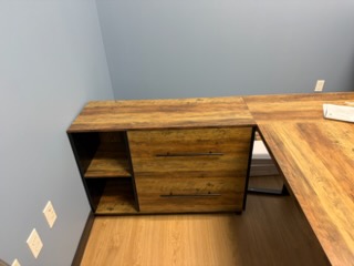 Wooden desk with storage cabinet and shelving unit in office corner