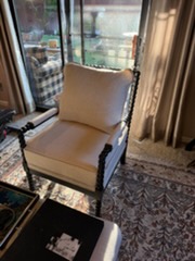 Beige upholstered armchair with wooden frame positioned near sliding glass doors in a hotel room