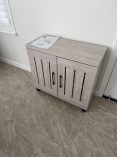 Light wood cabinet with vertical slat doors on tile flooring