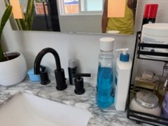 Organized bathroom vanity with skincare products, black headphones, and blue liquid soap bottle on marble surface