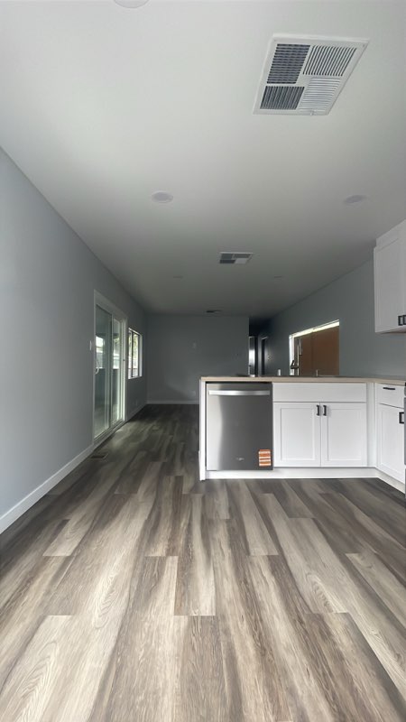Modern kitchen with white cabinets, stainless steel appliance, wood-grain flooring and gray walls